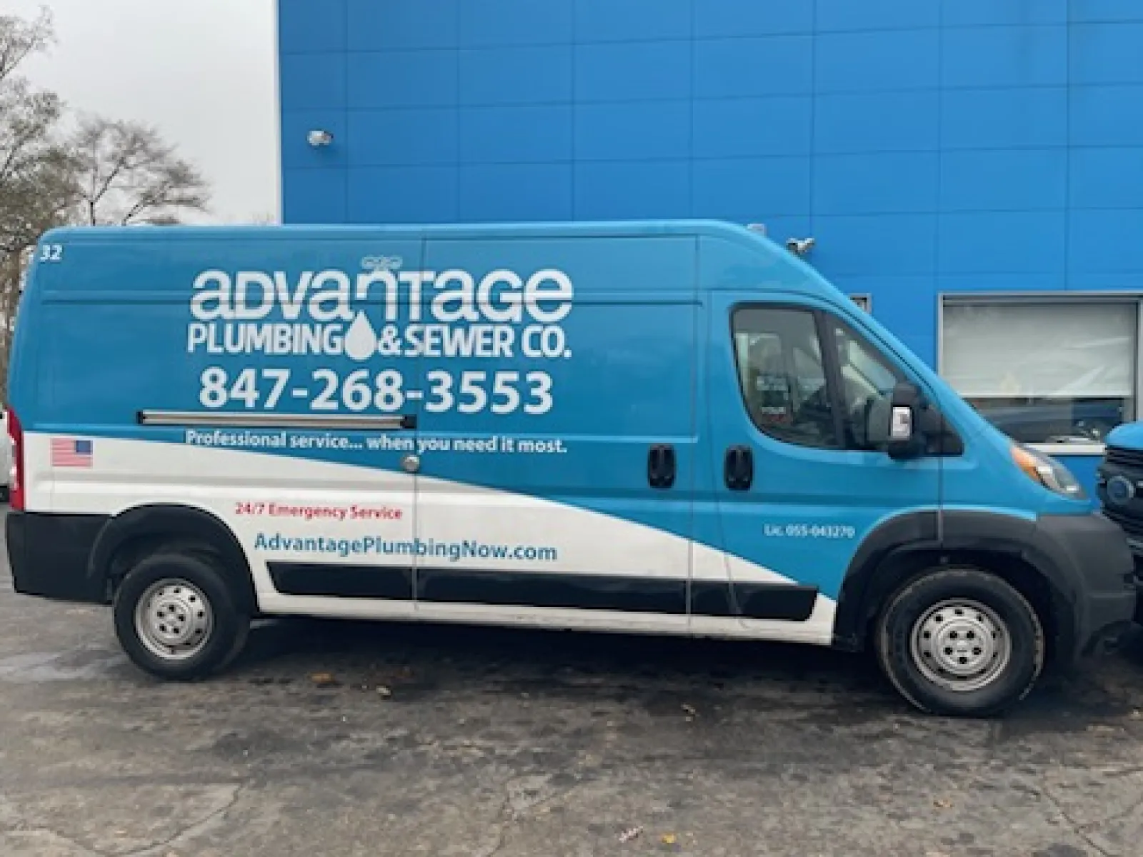 Blue and white Advantage Plumbing & Sewer Co. service van parked outside a blue building with contact details visible.