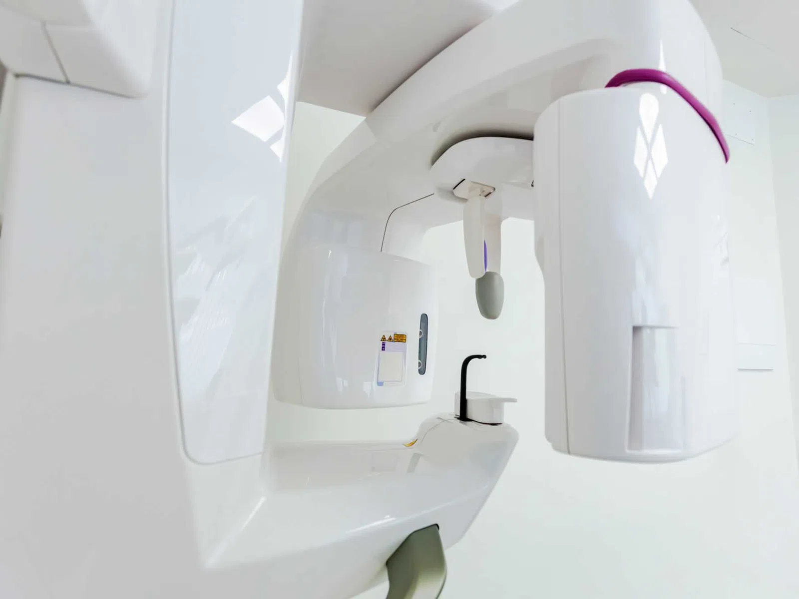 Bright modern dental clinic with dental chair, monitor, sink, and white cabinetry under natural light.
