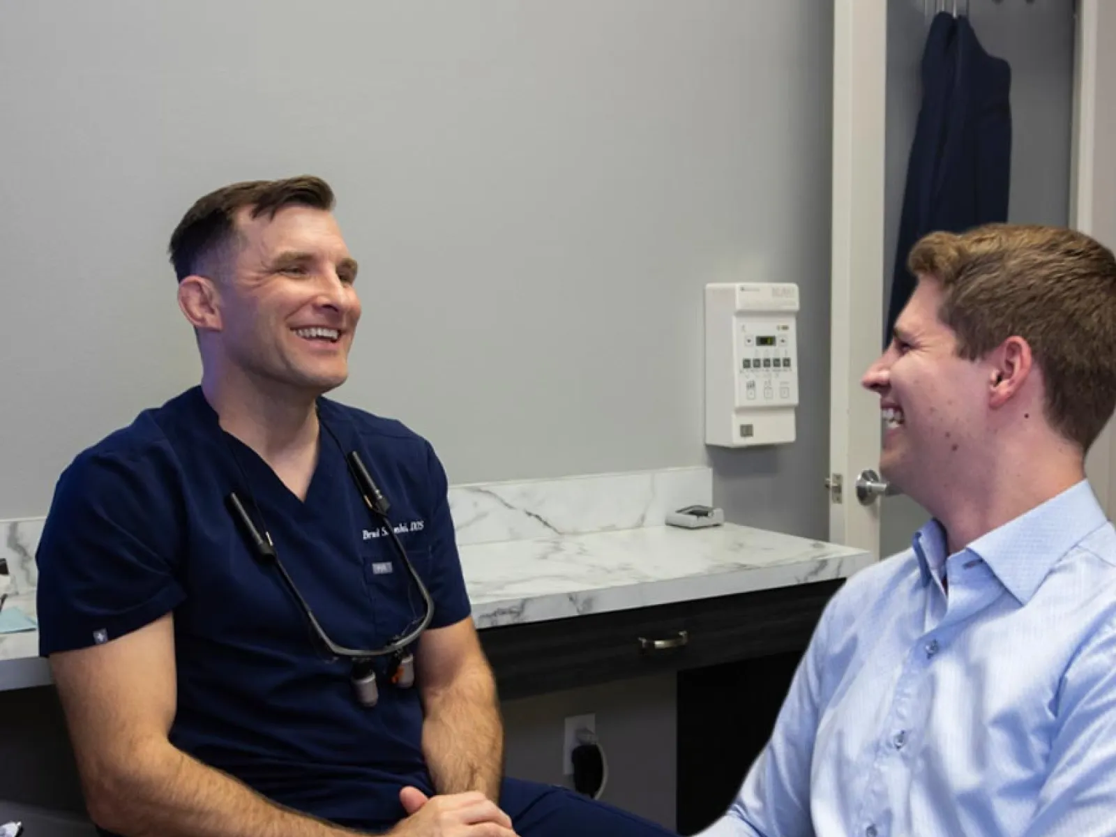Smiling male dentist and patient having a friendly consultation in a dental office with medical tools.