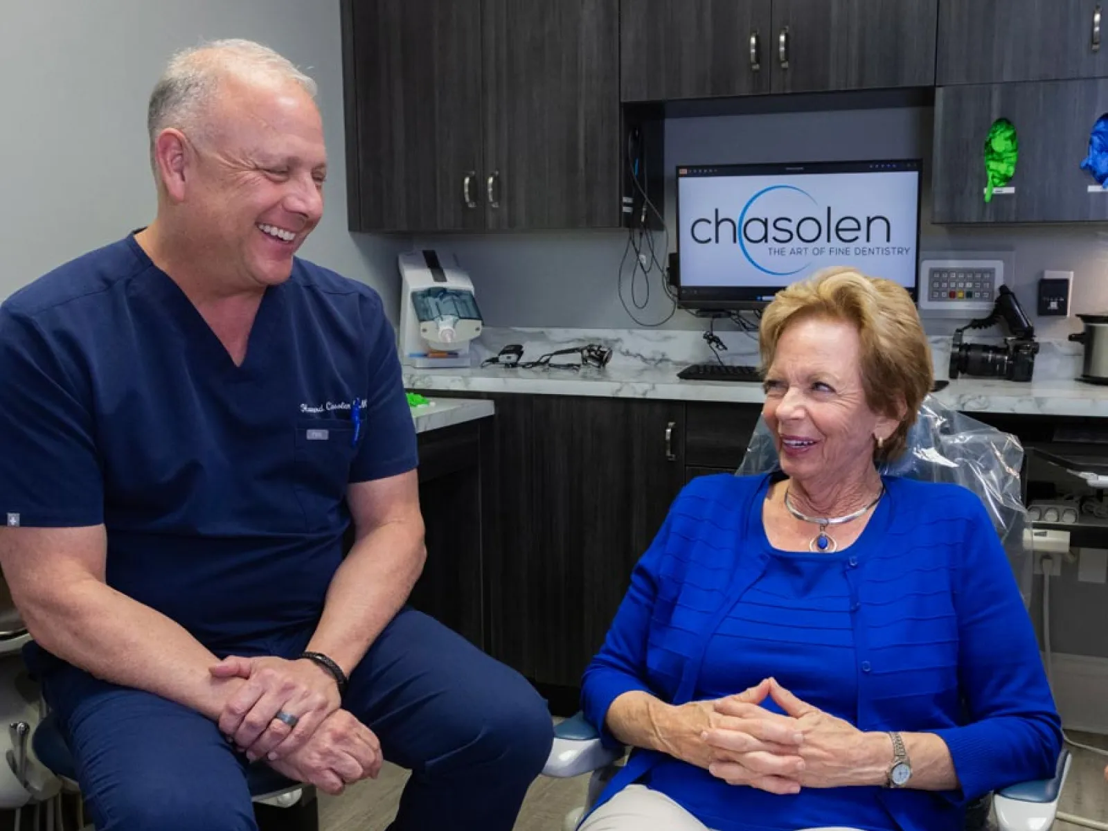 Smiling male dentist talking with elderly female patient in a modern dental office