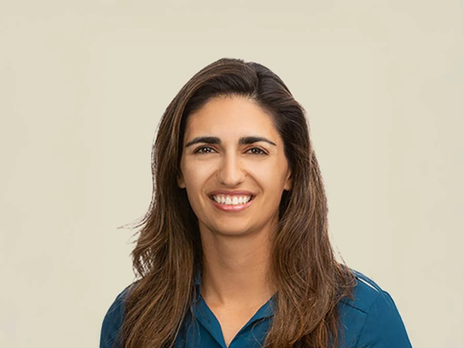 Professional woman smiling in a blue shirt against a light background.