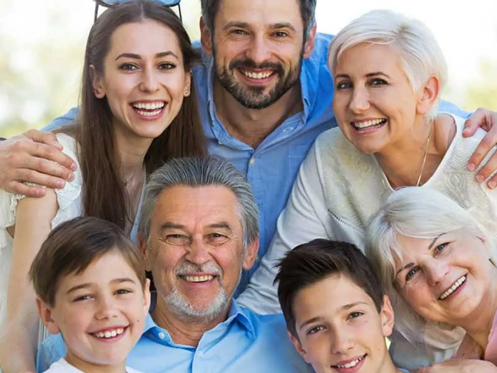 Happy multigenerational family smiling and embracing outdoors on a bright day together.