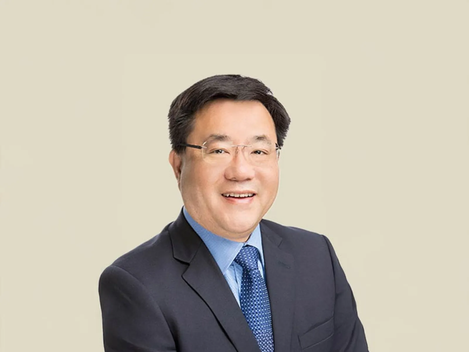 Smiling business professional in a suit, arms crossed, with a neutral background.
