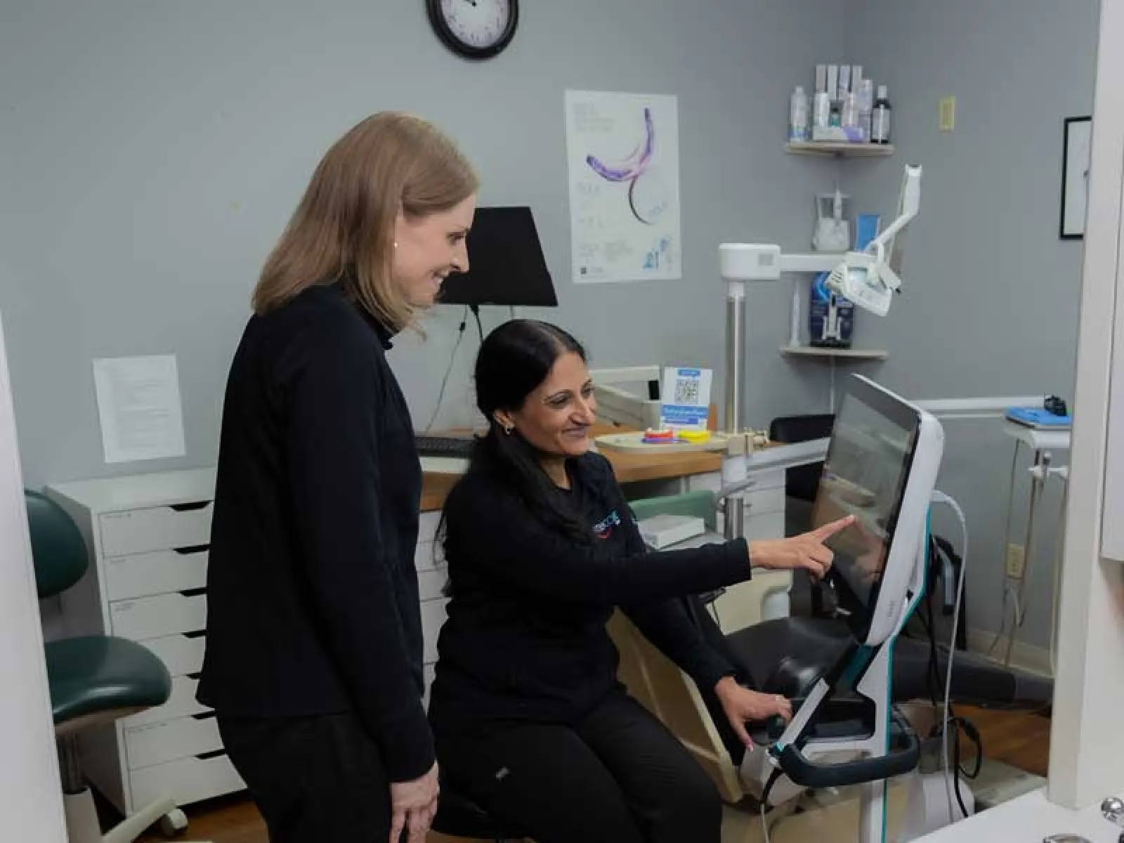 Dentist explaining digital dental X-ray results to patient in modern dental office setting