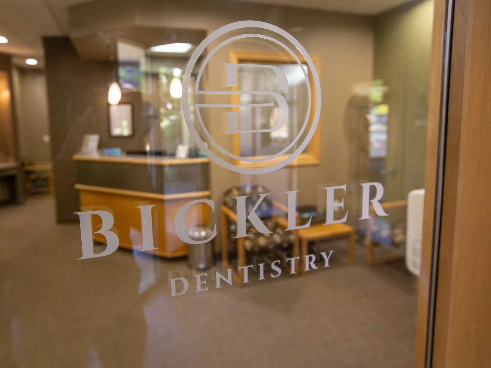Glass door with Bickler Dentistry logo showing a welcoming dental office reception area inside.