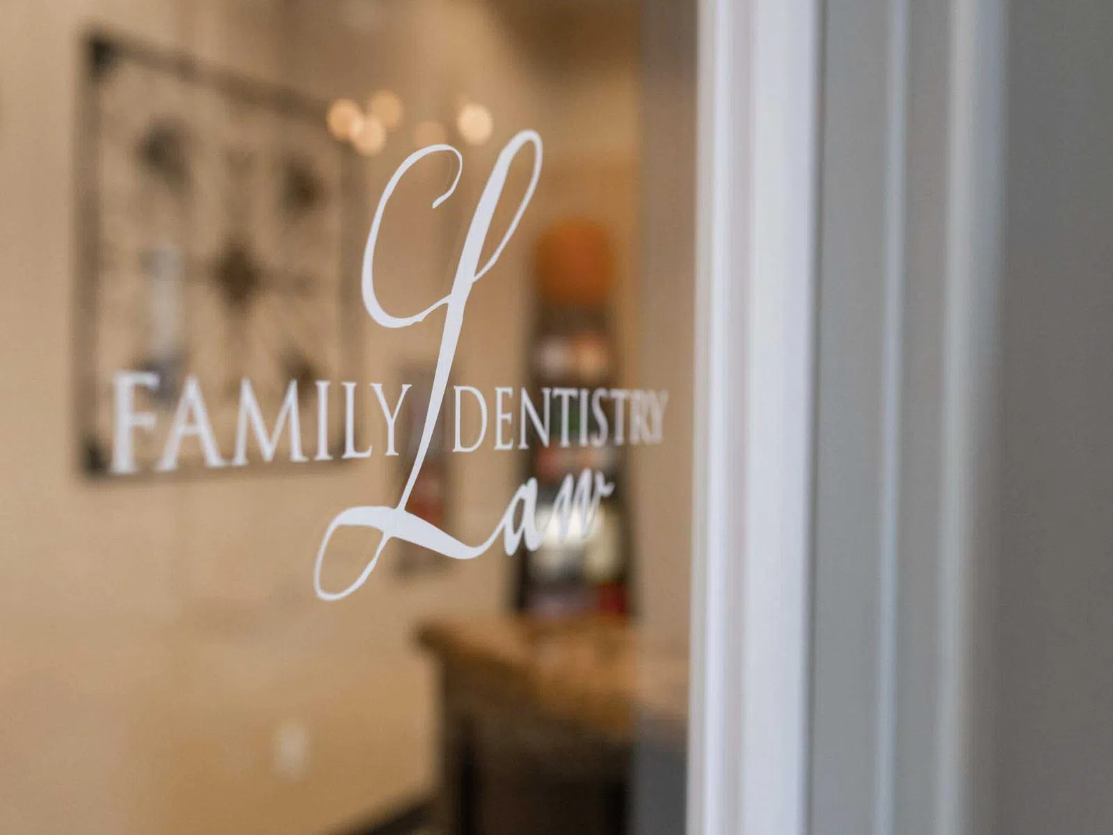 Glass door with white lettering for Family Dentistry Law office in a softly lit interior.
