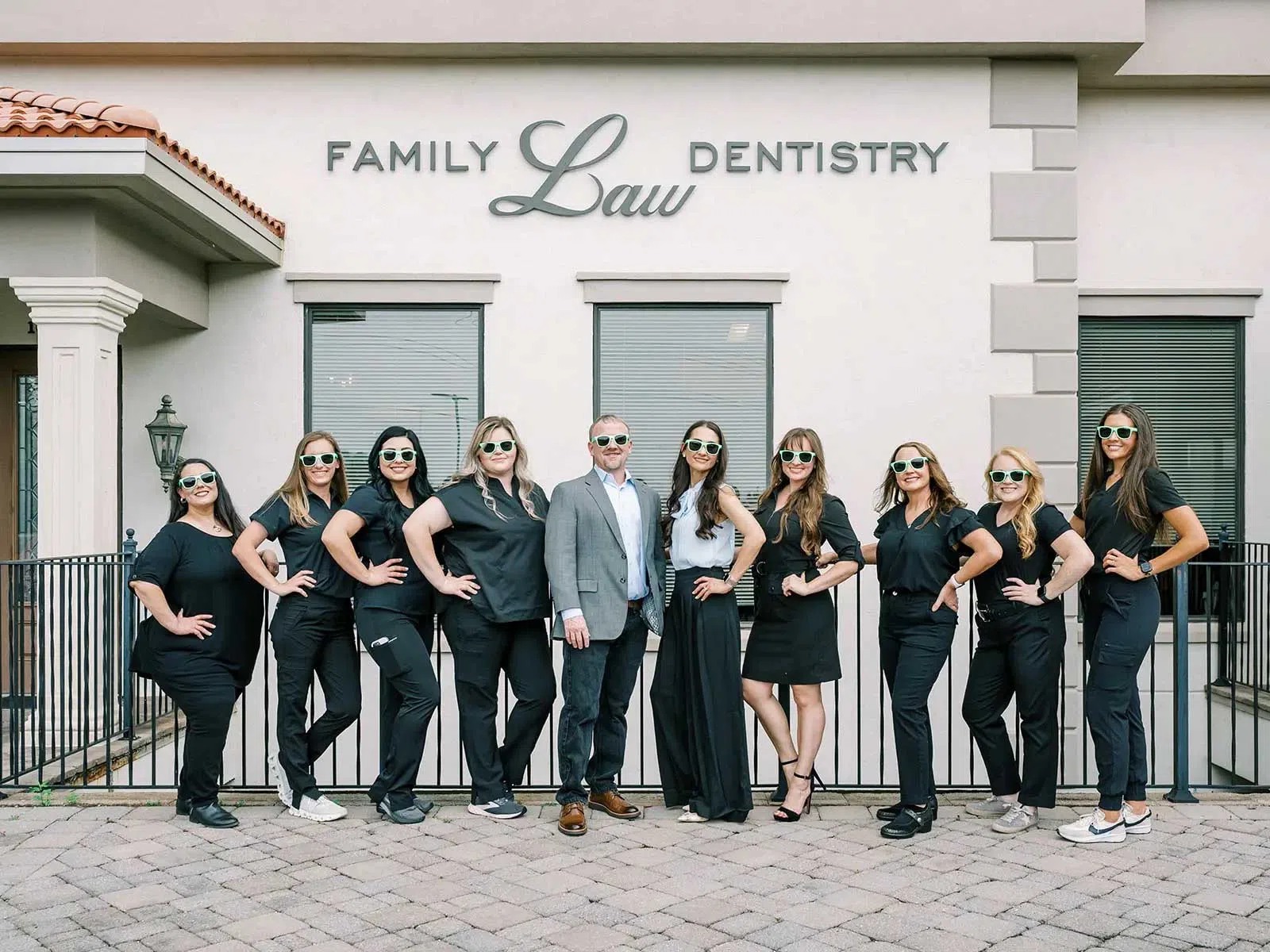 Dental team in black outfits posing confidently outside Family Law Dentistry wearing sunglasses