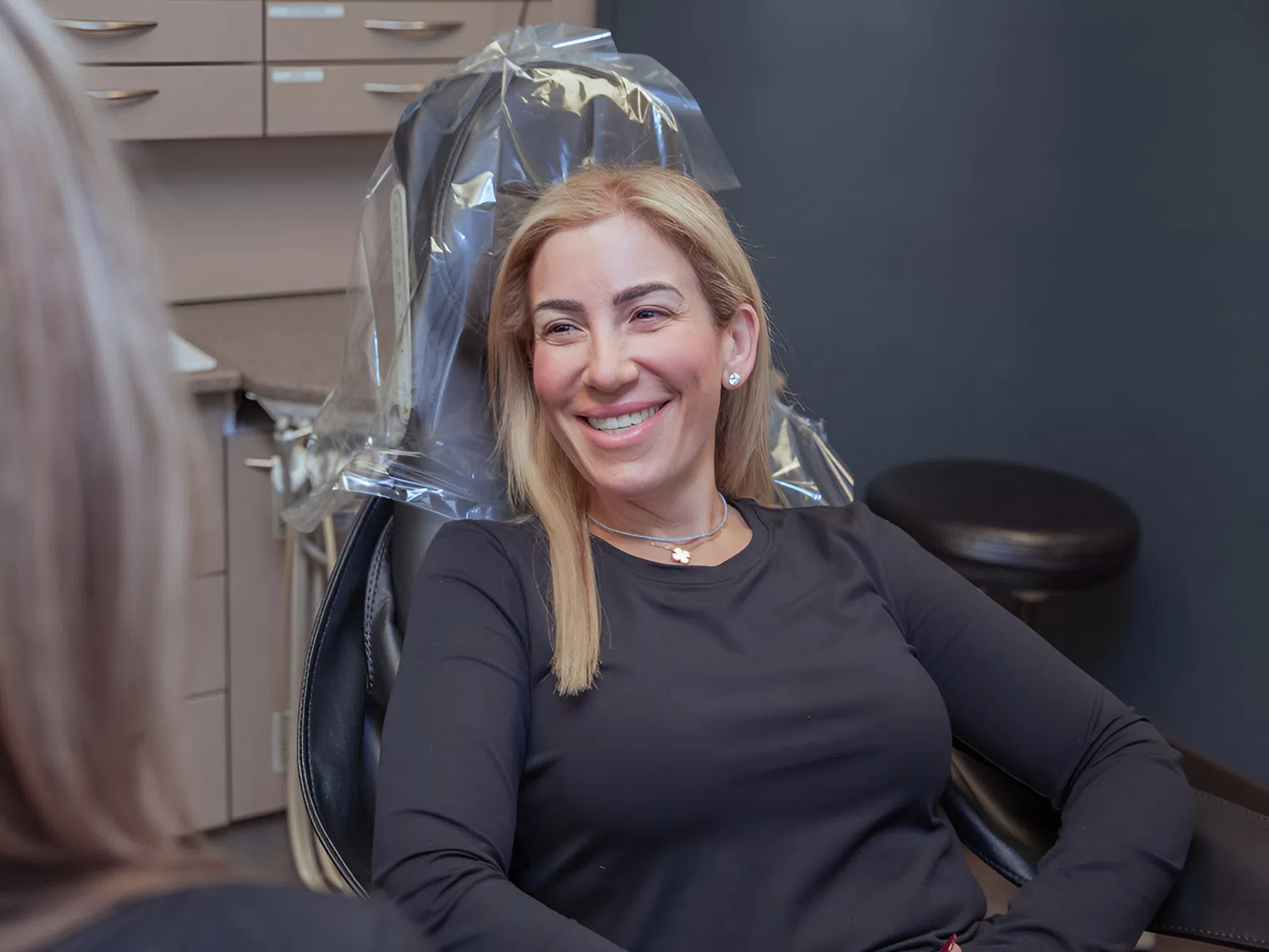 Smiling woman sitting in a dental chair during a consultation in a modern dental office