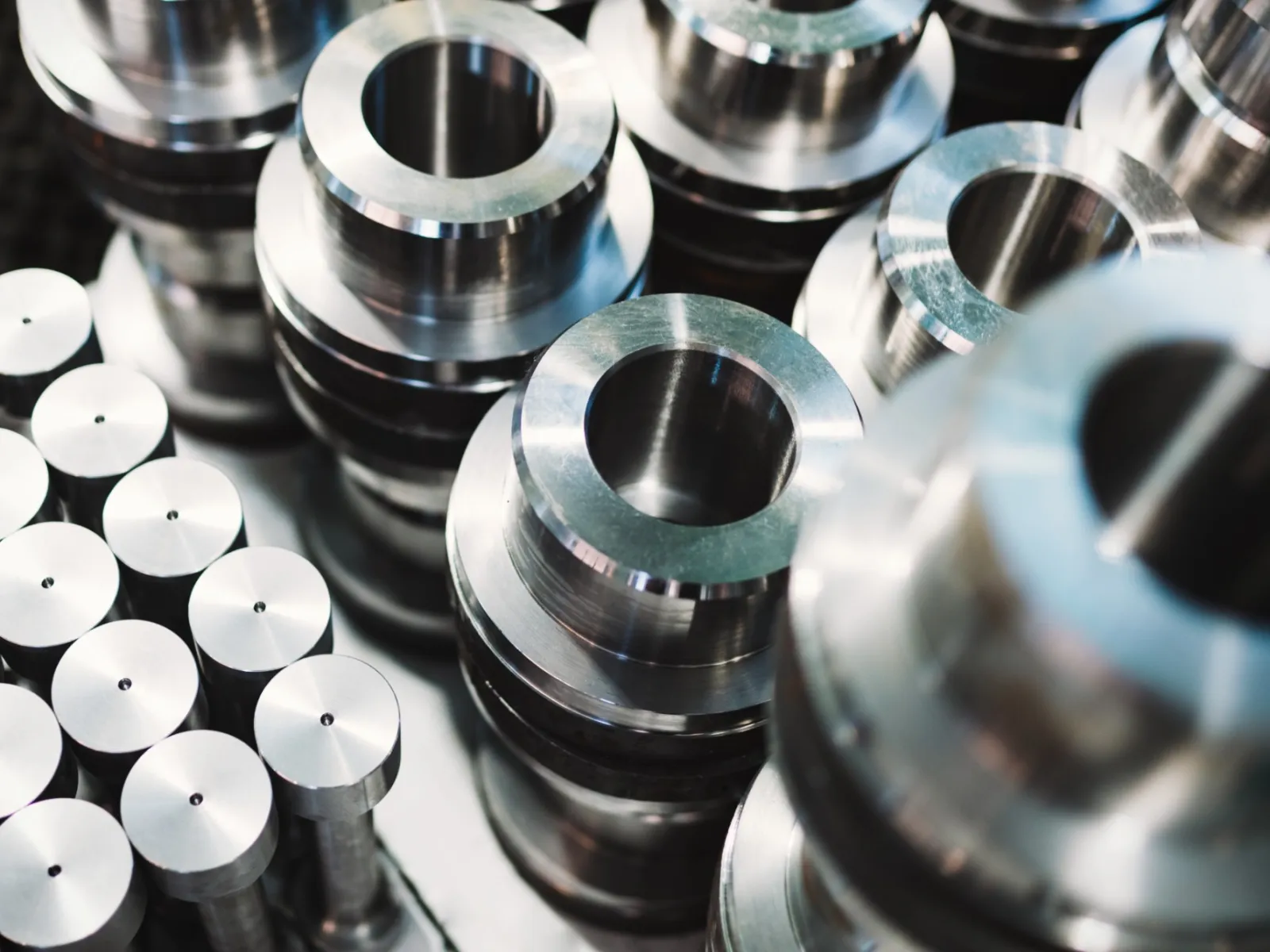 Close-up of shiny machined metal parts and cylindrical components arranged in industrial setting