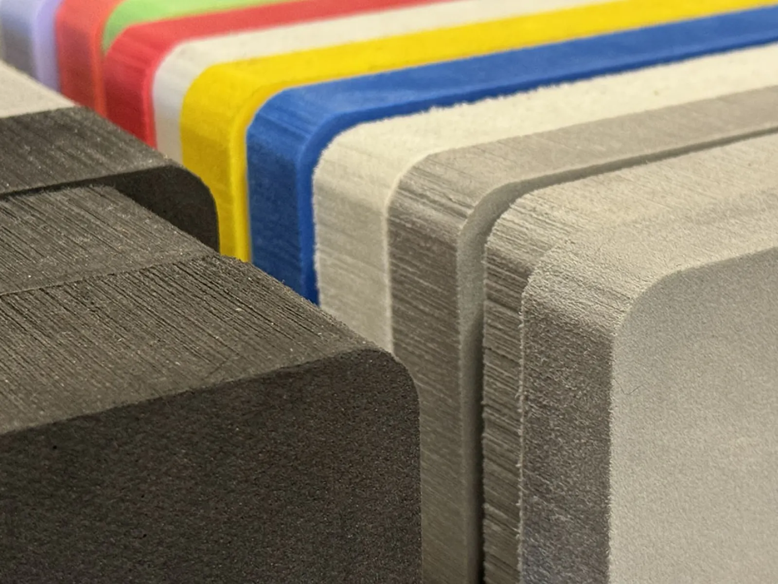 Close-up of stacked colorful foam sheets with rounded edges showing texture and layers.