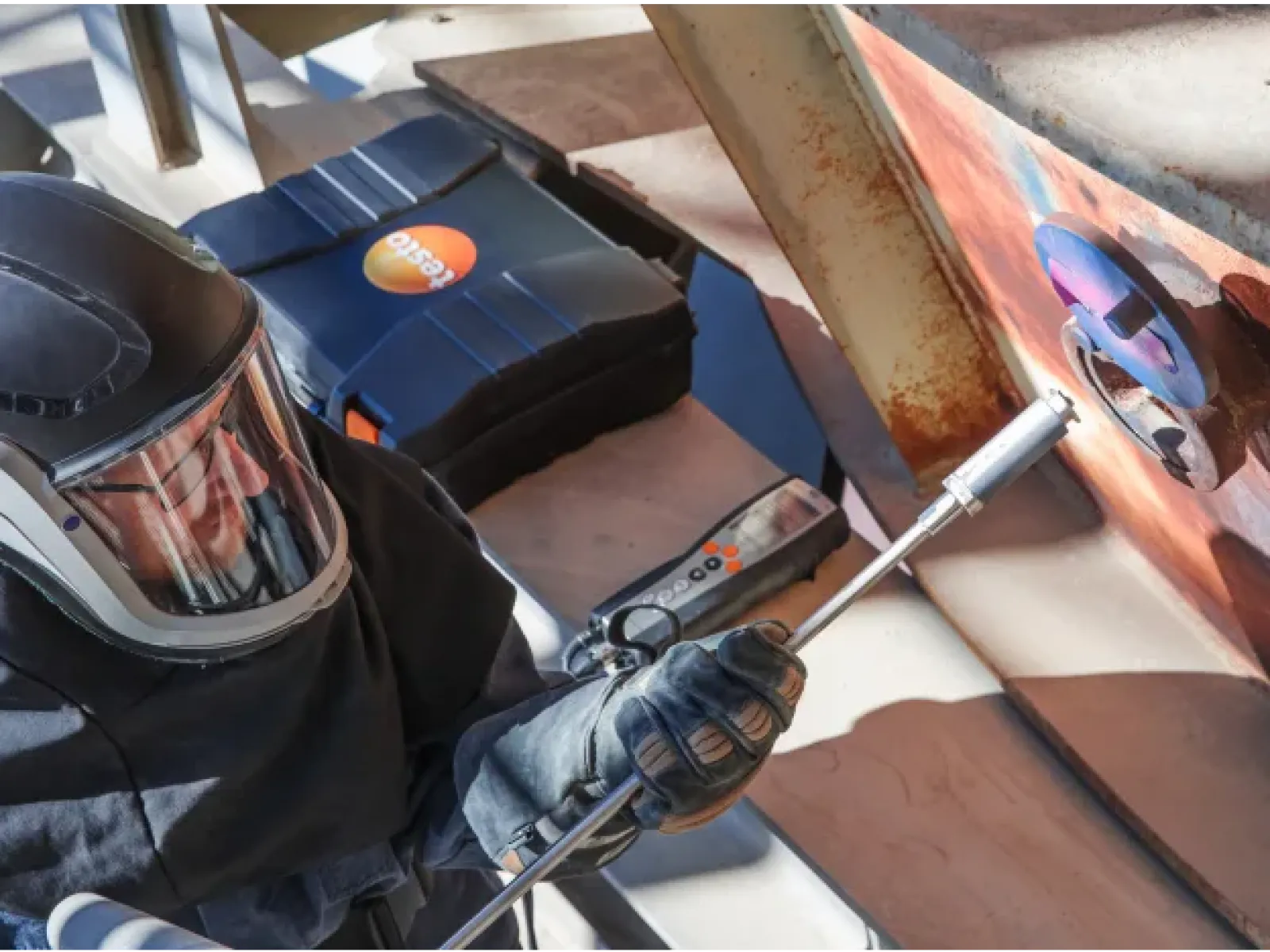 Worker in protective gear using a combustion gas analyzer to test emissions.