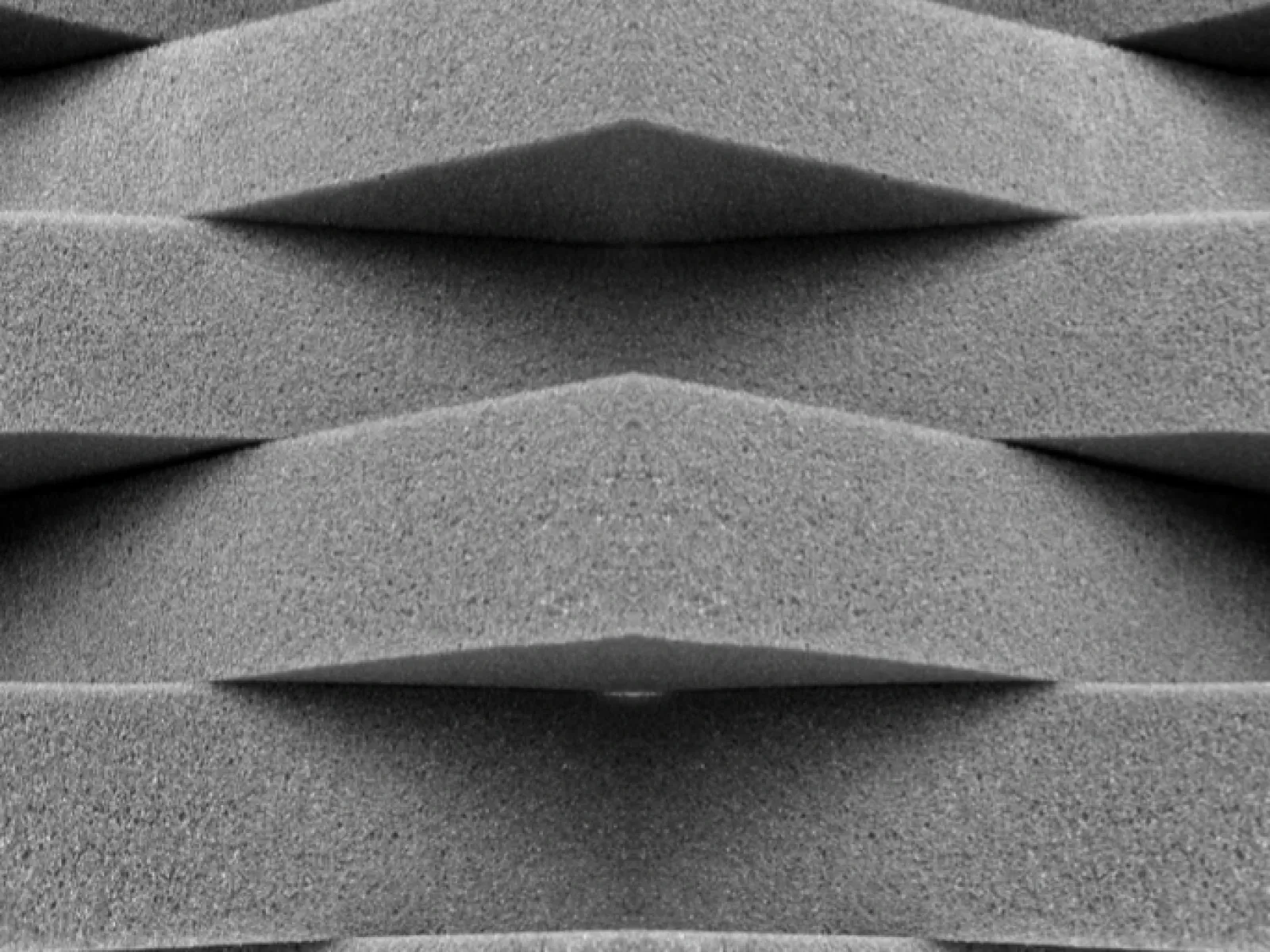 Close-up of textured gray foam layers with geometric overlapping patterns and soft shadows.