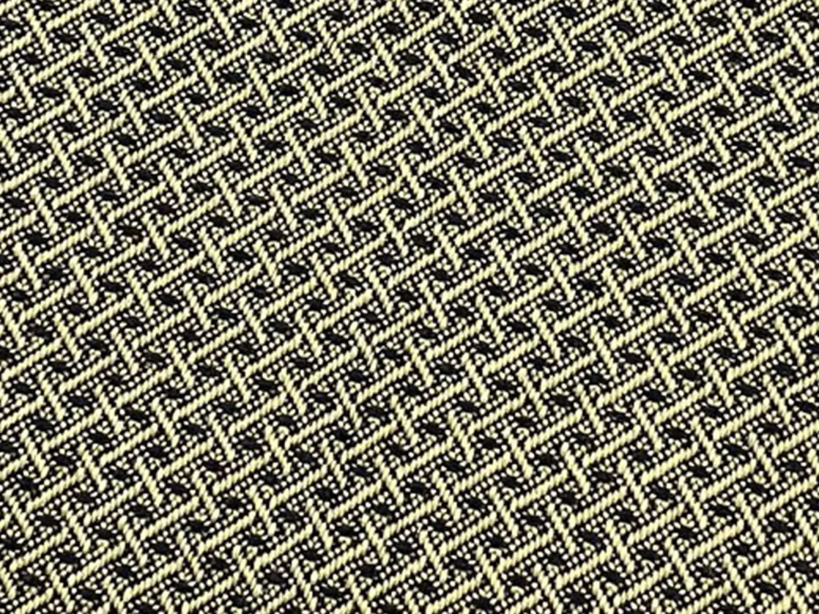 Close-up of textured fabric with a woven pattern in black and beige threads creating a geometric design.