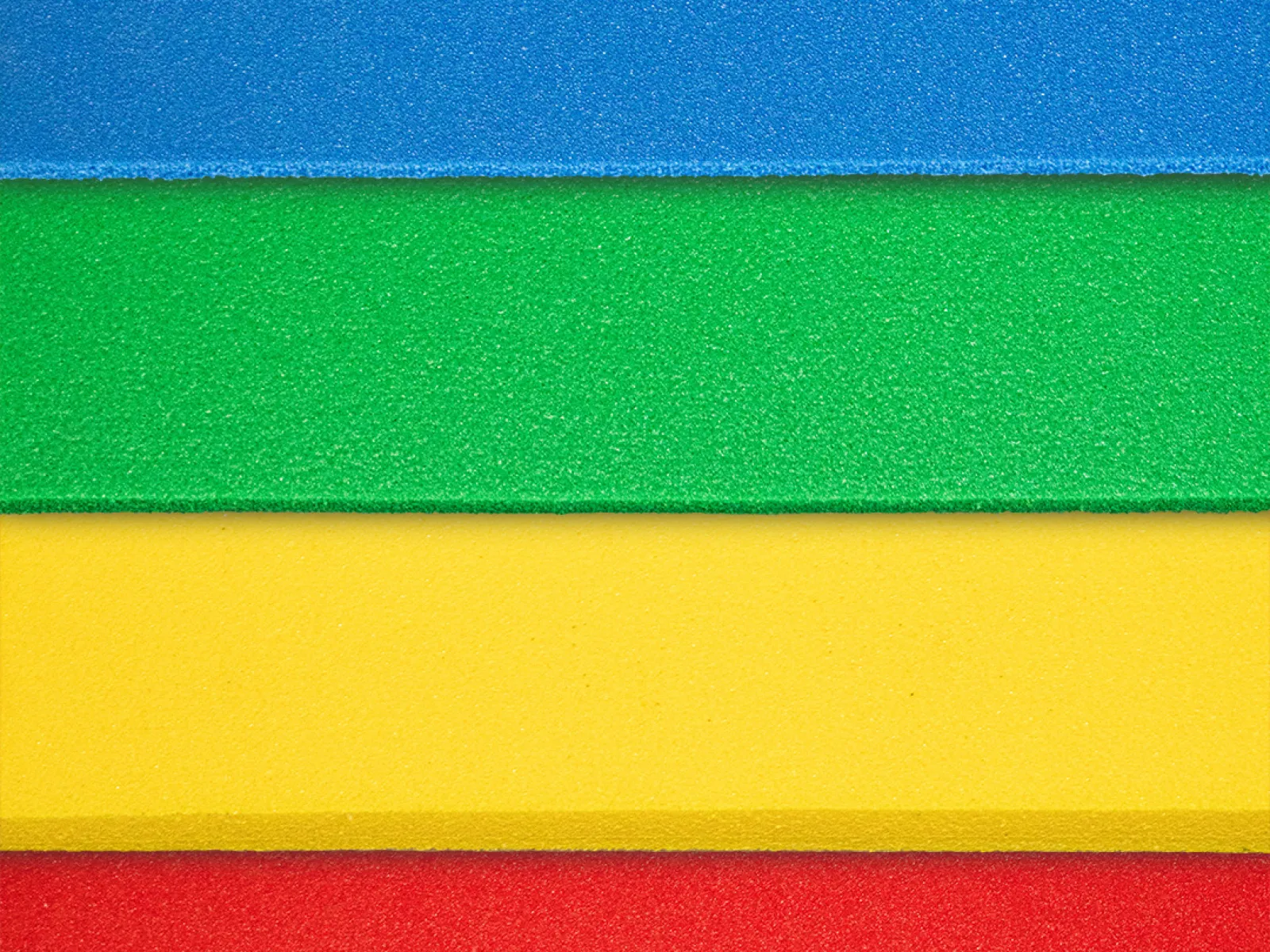 Close-up of textured foam sheets in blue, green, yellow, and red colors arranged horizontally.