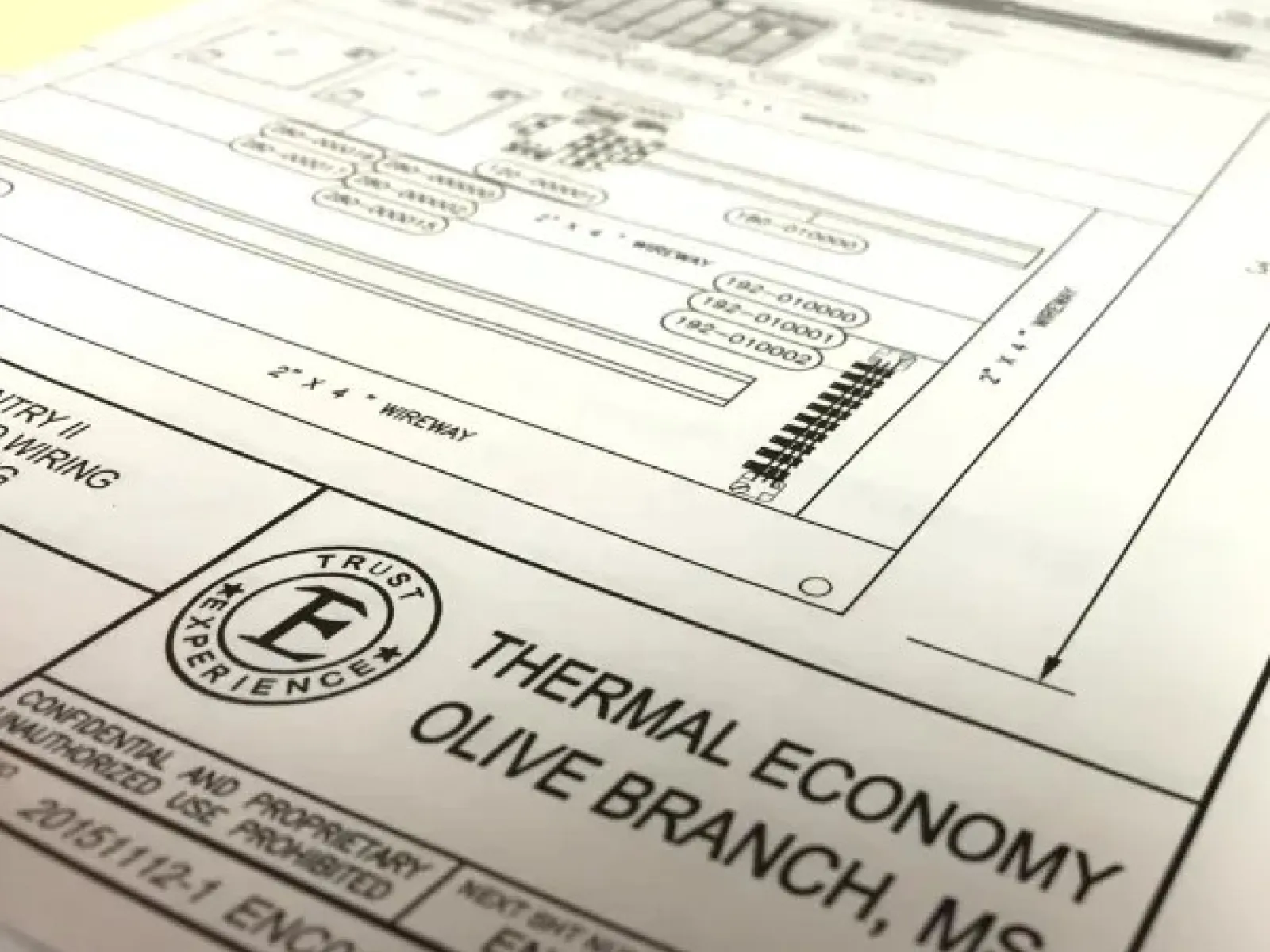 Close-up of architectural blueprints labeled Thermal Economy Olive Branch, MS on wooden table.