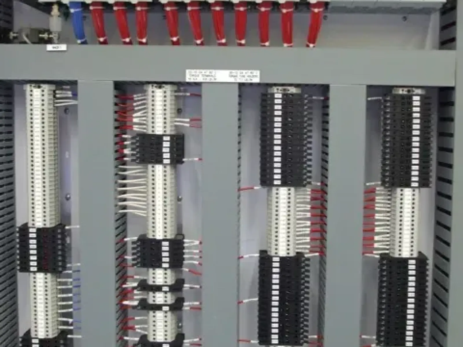 Industrial control panel with multiple wiring terminals, circuit breakers, and PLC modules organized in a metal cabinet.