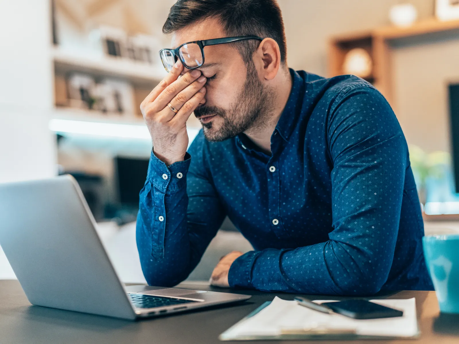 a man with his hand on his face looking at a laptop