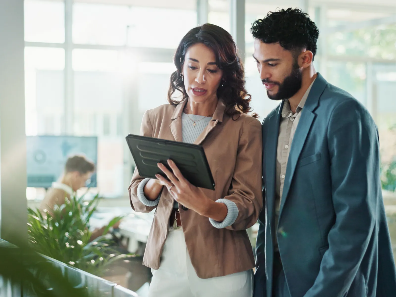 Two business professionals collaborating and reviewing information on a digital tablet in a modern office.