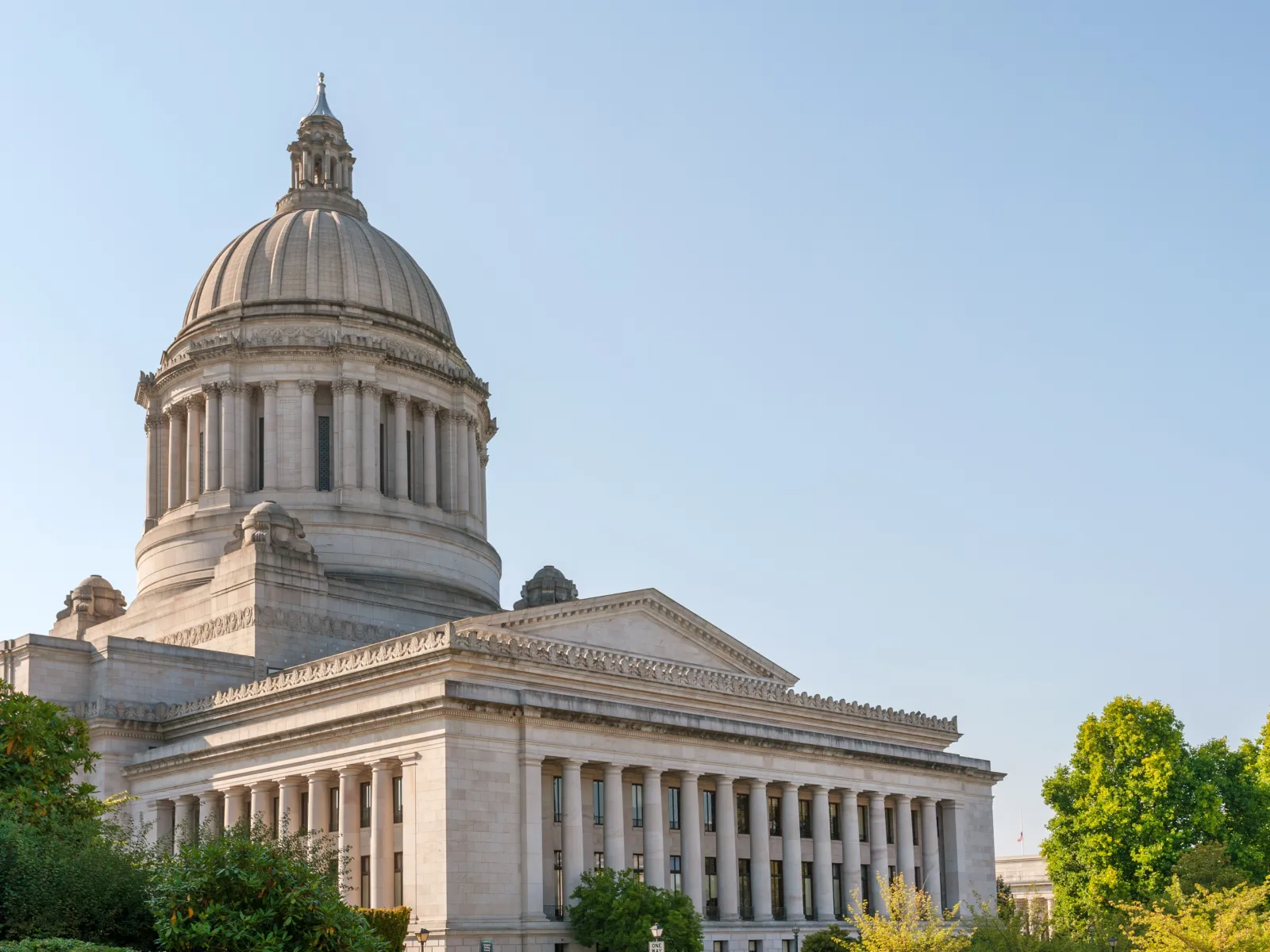 Washington State Capitol building with white dome and classical columns under clear blue sky.