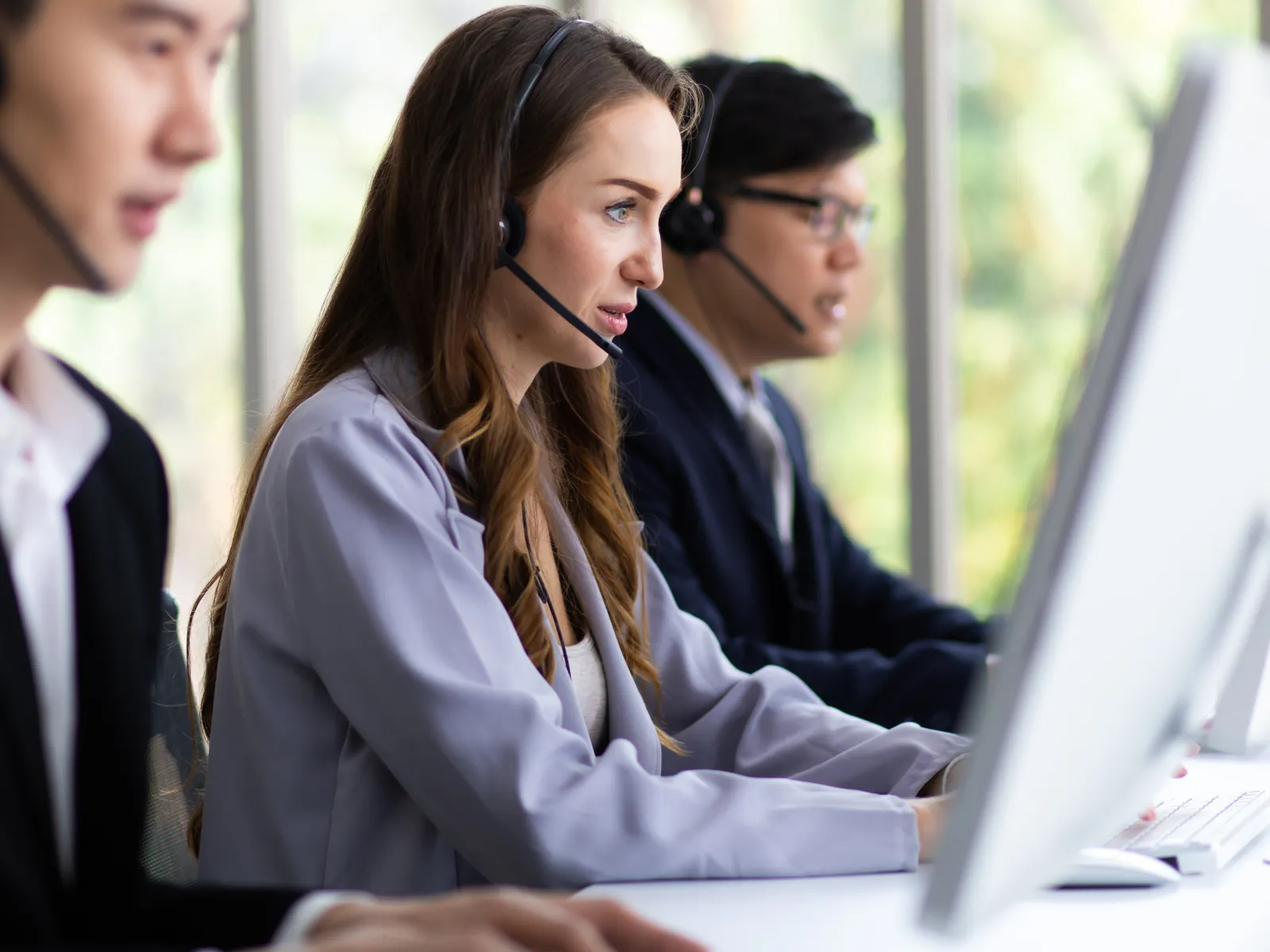 Customer service team wearing headsets working on computers in a modern office environment