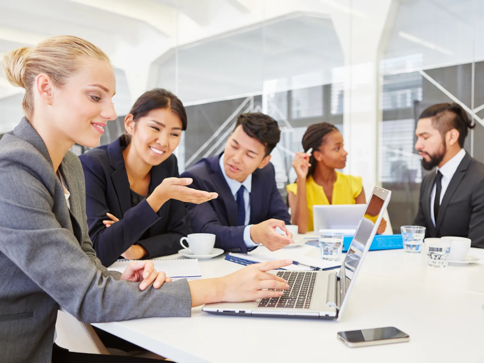 Diverse business team discussing work around a laptop during a meeting in a modern office space