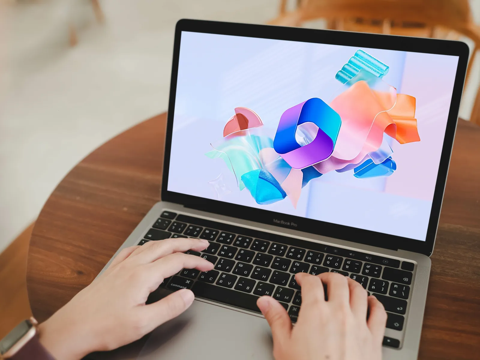 Person typing on a MacBook Air with colorful abstract shapes displayed on the laptop screen.