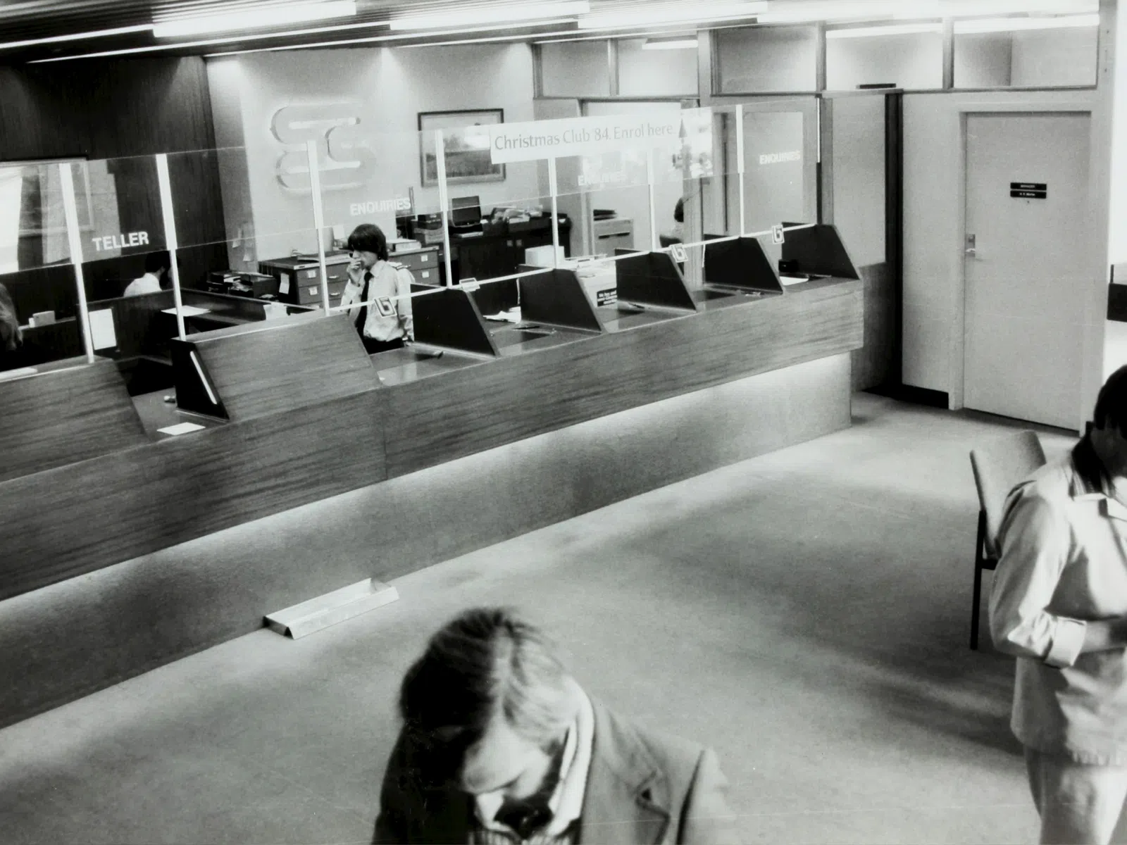 Young woman working on computer at standing desk in industrial warehouse or workshop environment.