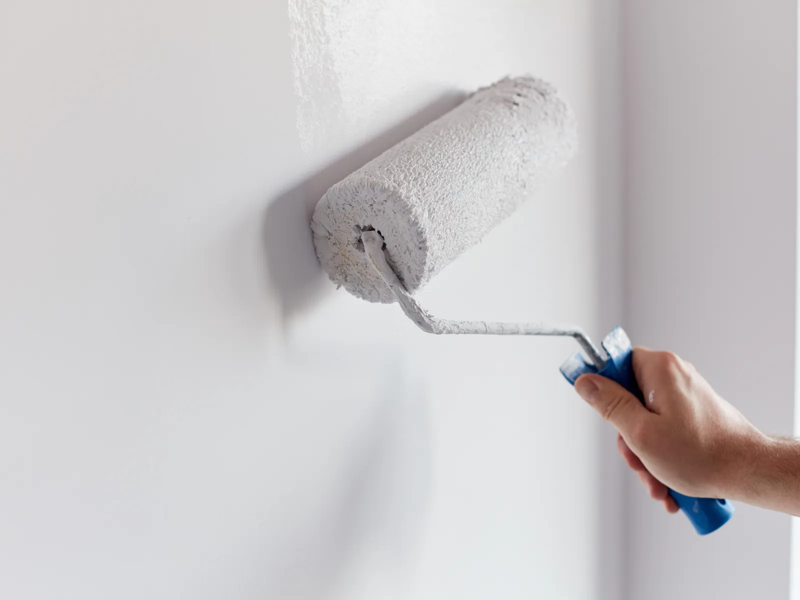 a hand holding a paint roller, painting the room