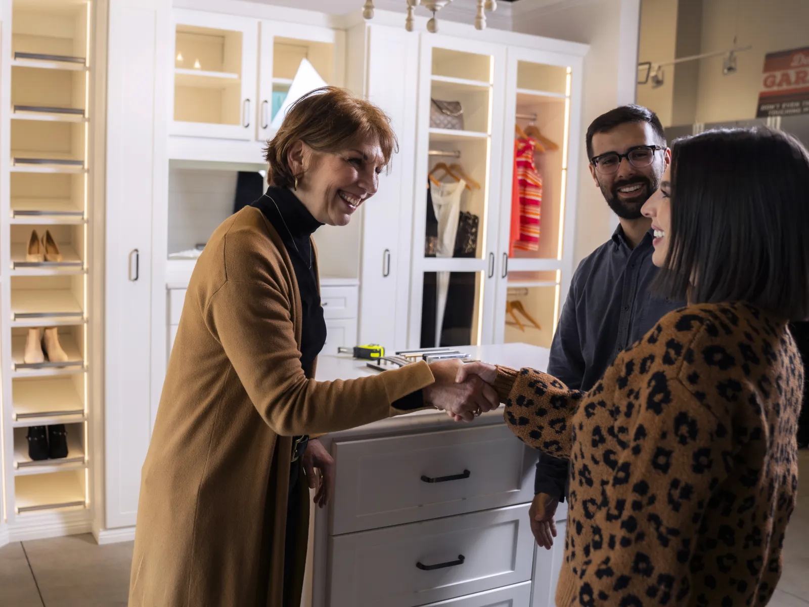 a man and woman standing in a room with shelves and cabinets