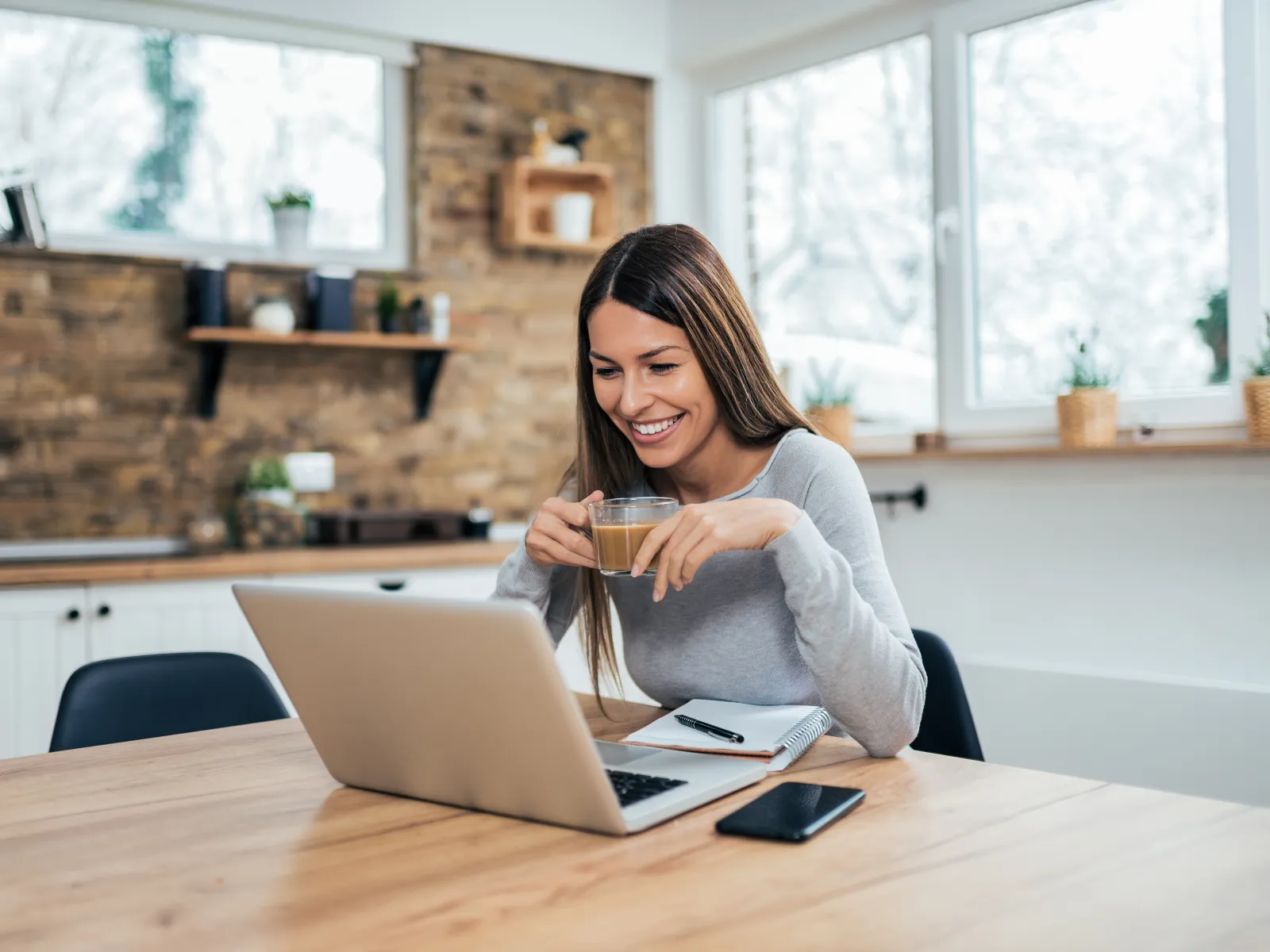 a woman sitting at a table with a laptop and a phone
