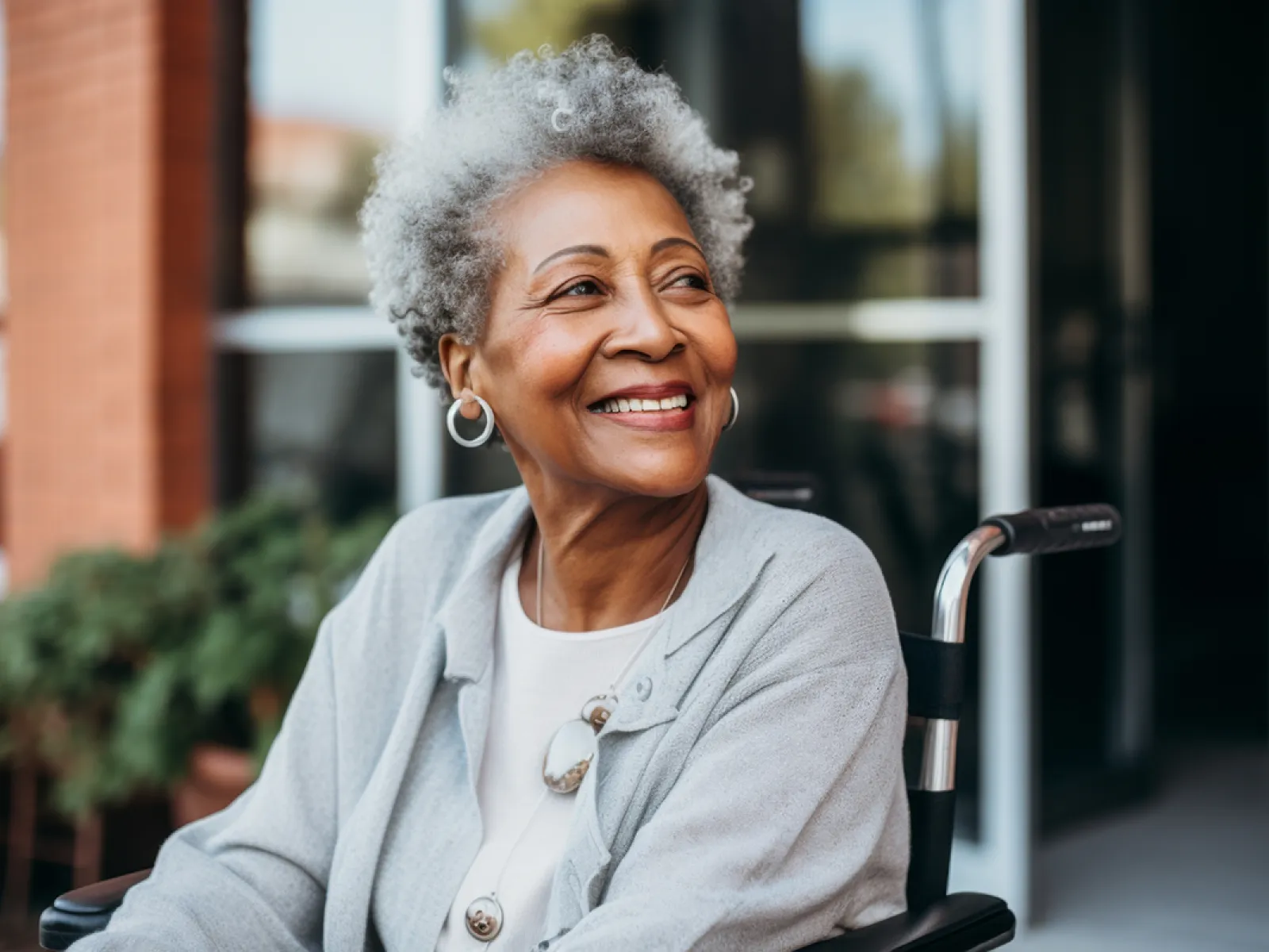 Smiling elderly woman with gray hair in a wheelchair, outdoors, showcasing joy and wisdom.