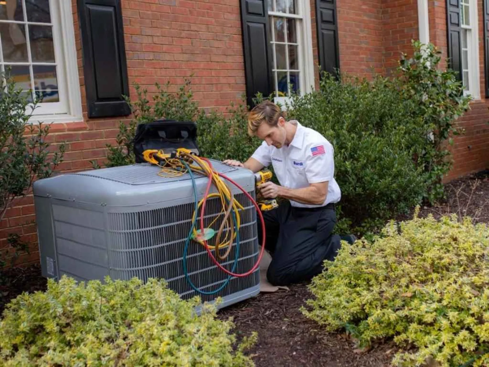 HVAC technician performing AC maintenance on residential outdoor condenser unit in Atlanta, GA
