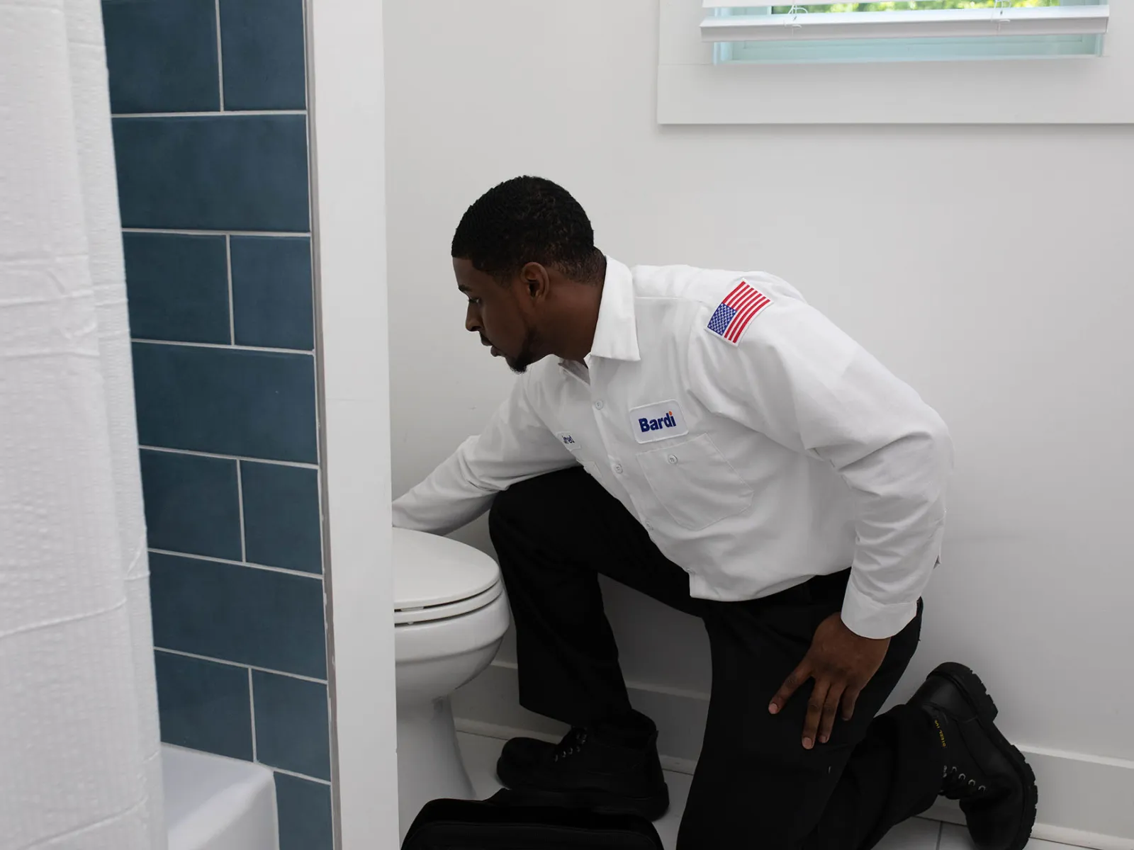 A professional plumber servicing a toilet in sandy springs modern bathroom setting.