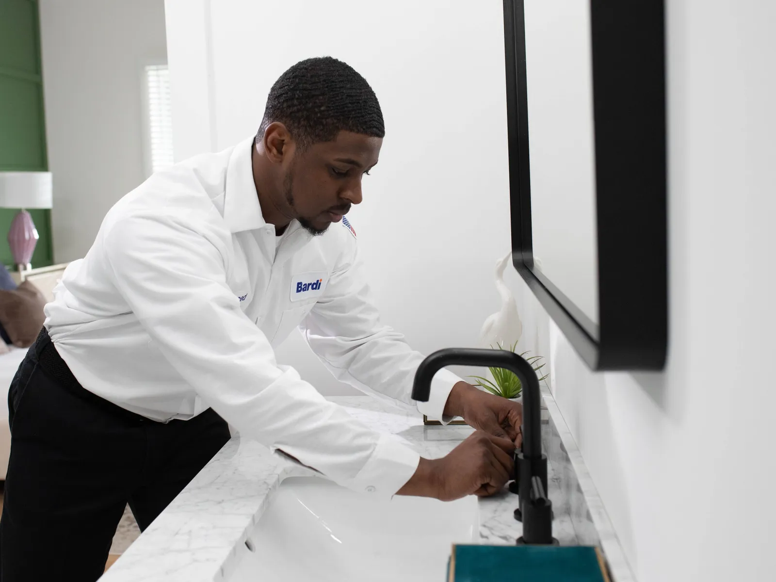 A professional plumber installs a modern faucet in a stylish bathroom setting.