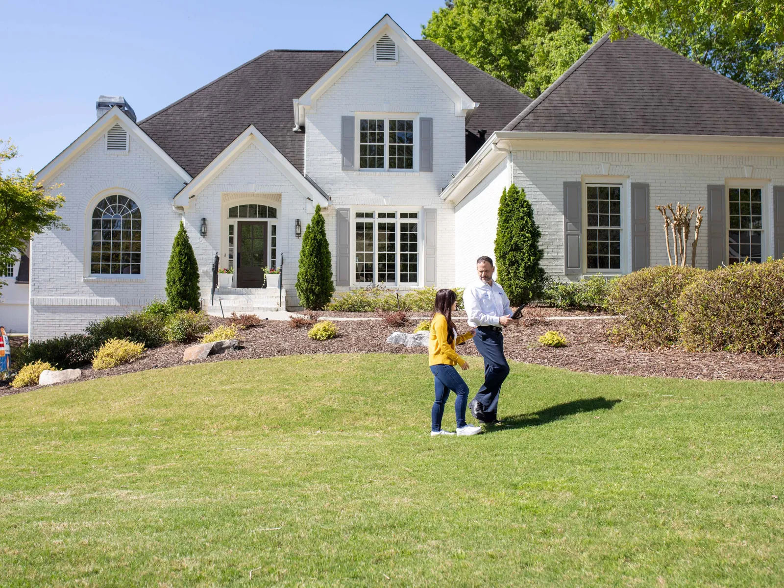 a man and a woman walking in front of a house