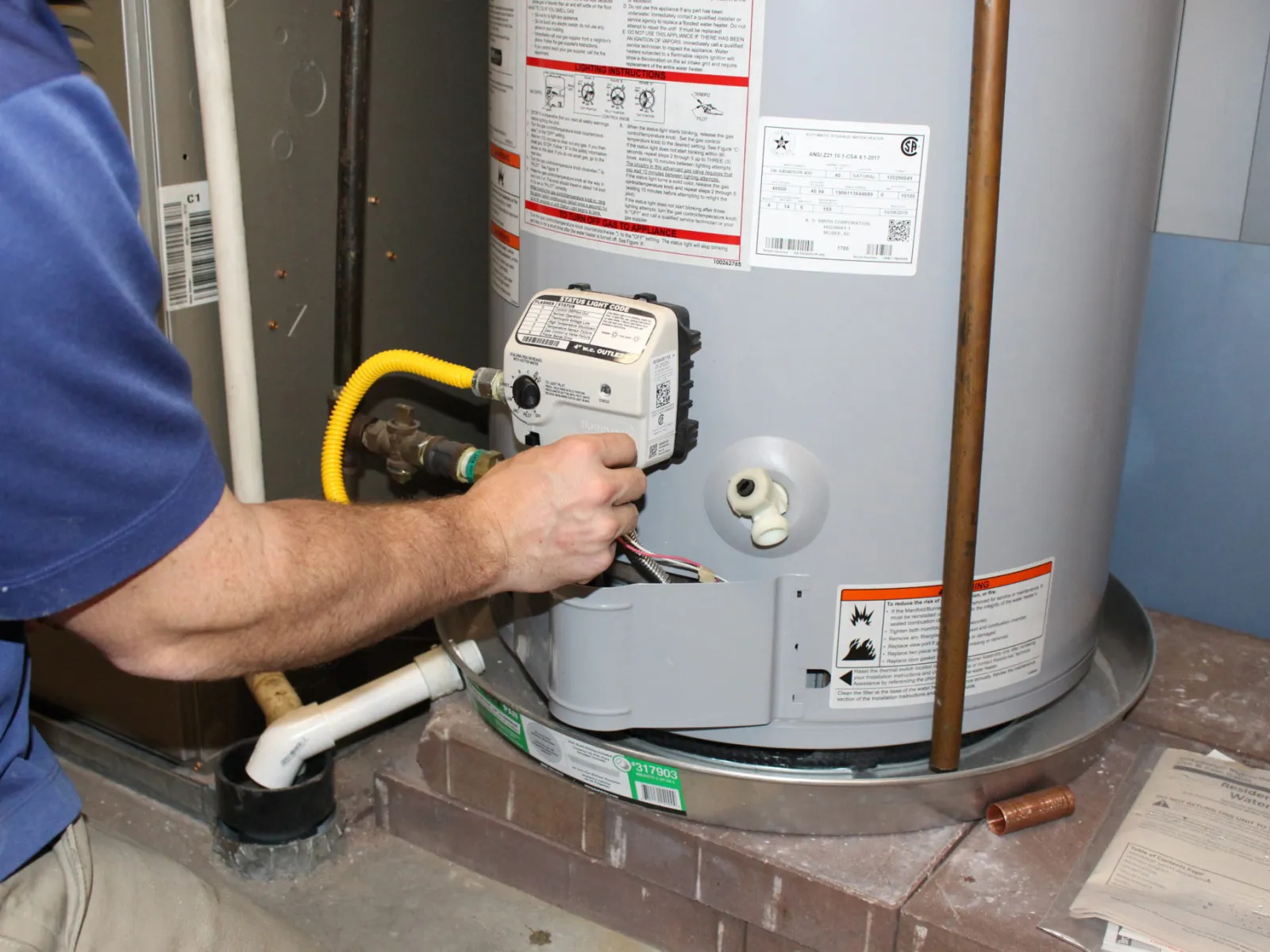 Technician working on a hot water heater, focusing on the wiring and control panel.