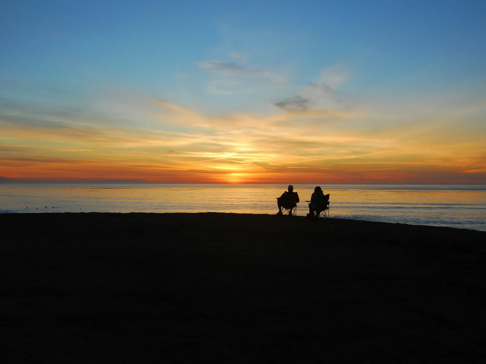 a couple of people riding horses on a beach
