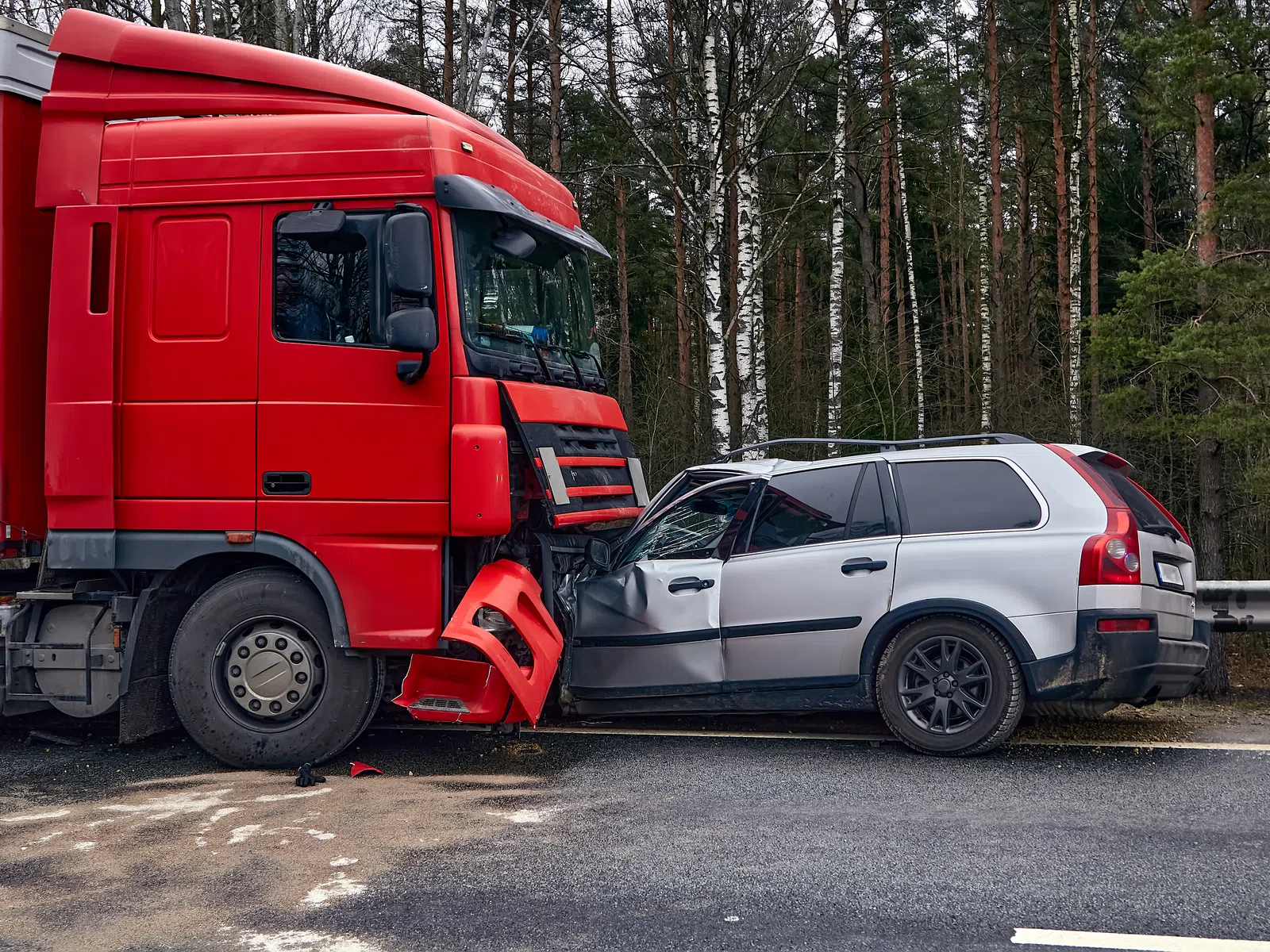 Red truck collided head-on with silver station wagon on roadside near forested area causing front-end damage.