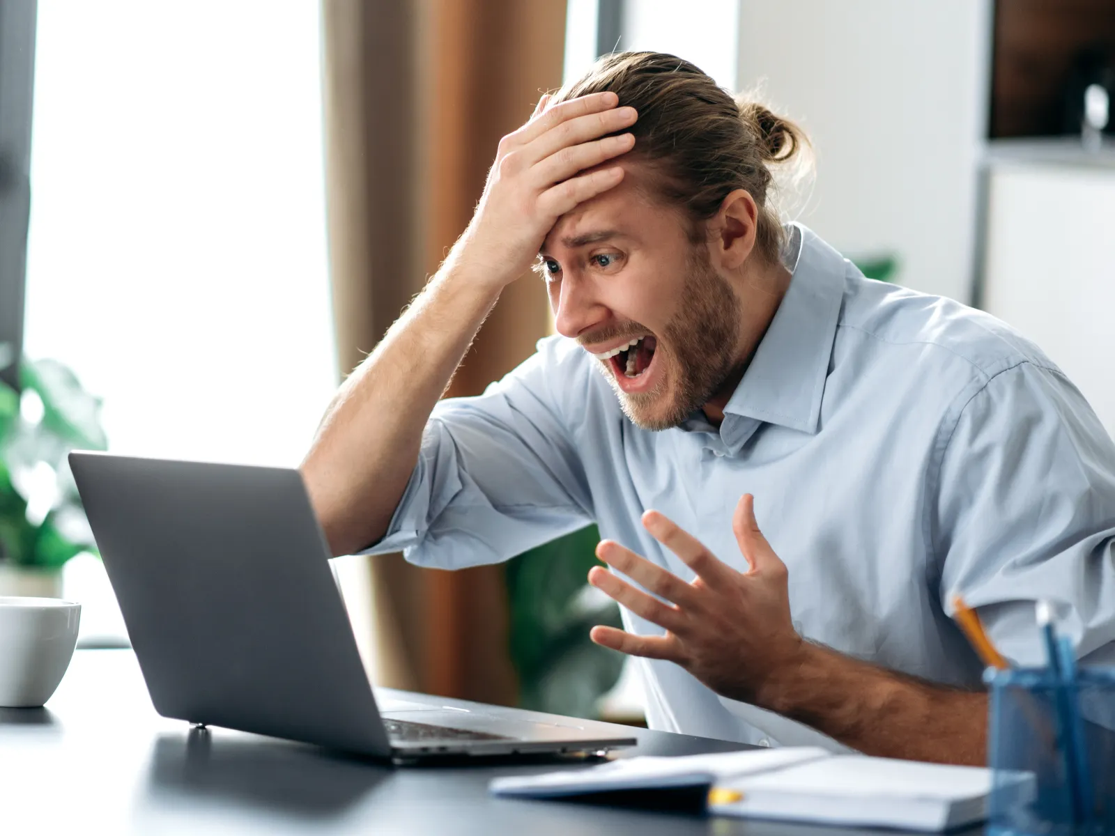 a man with his hands on his head looking at a laptop