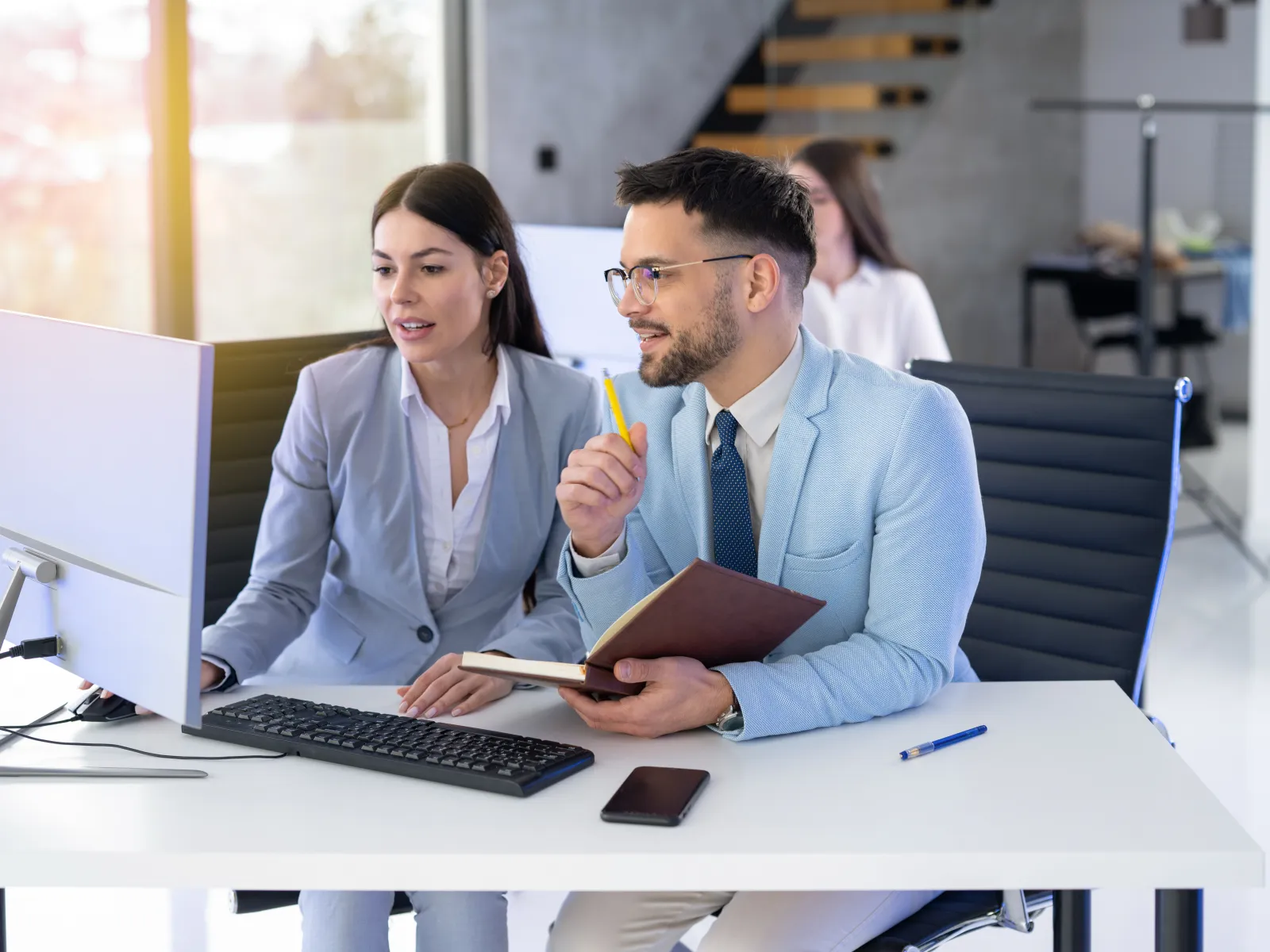 a man and a woman sitting at a table with a computer