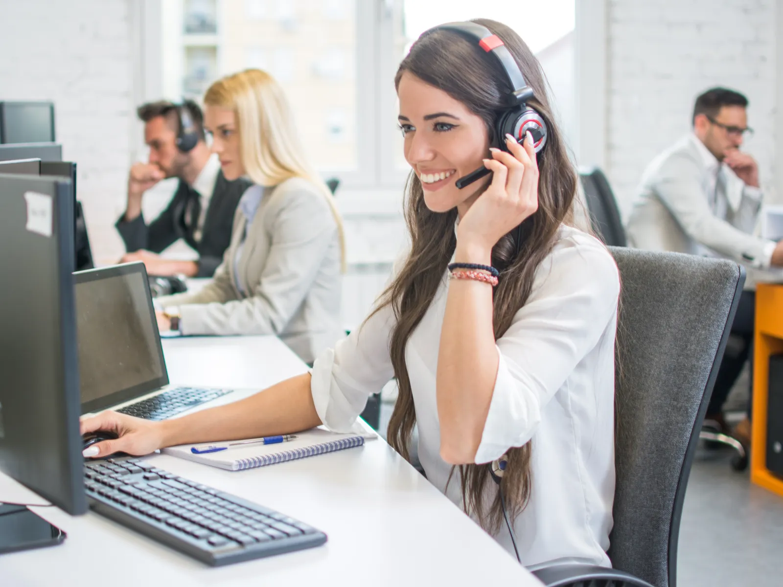 a woman wearing headphones and sitting at a desk with a laptop