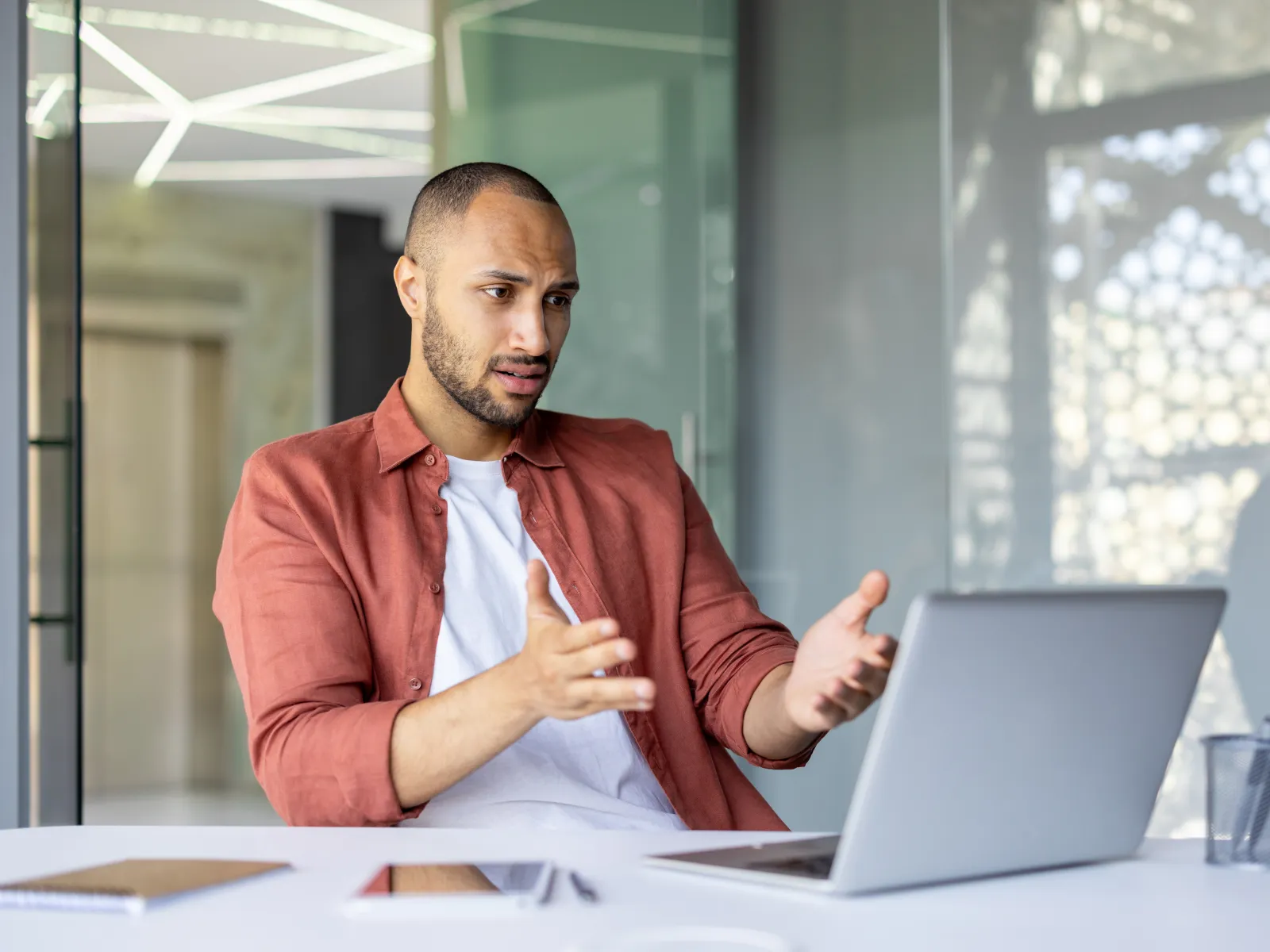 a man sitting at a table with a laptop and a window