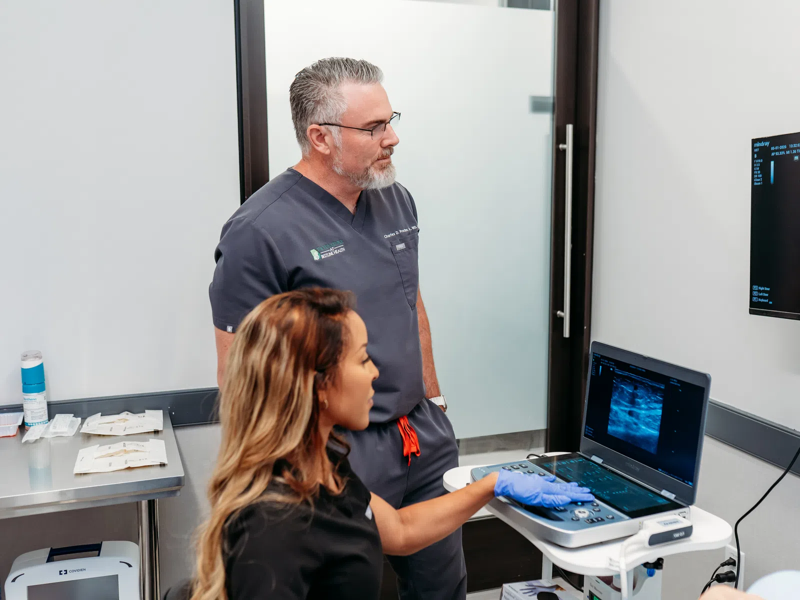 Medical professionals analyzing ultrasound images on a laptop and monitor during a diagnostic session.