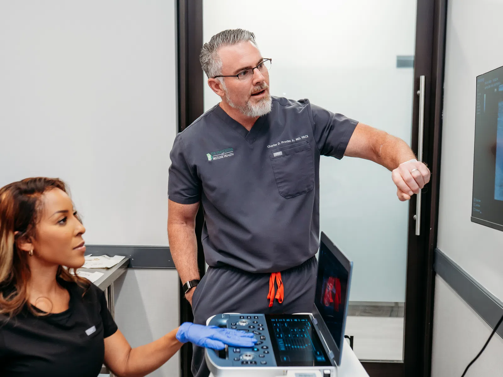 Doctor explains ultrasound results to patient using medical imaging equipment in clinic room
