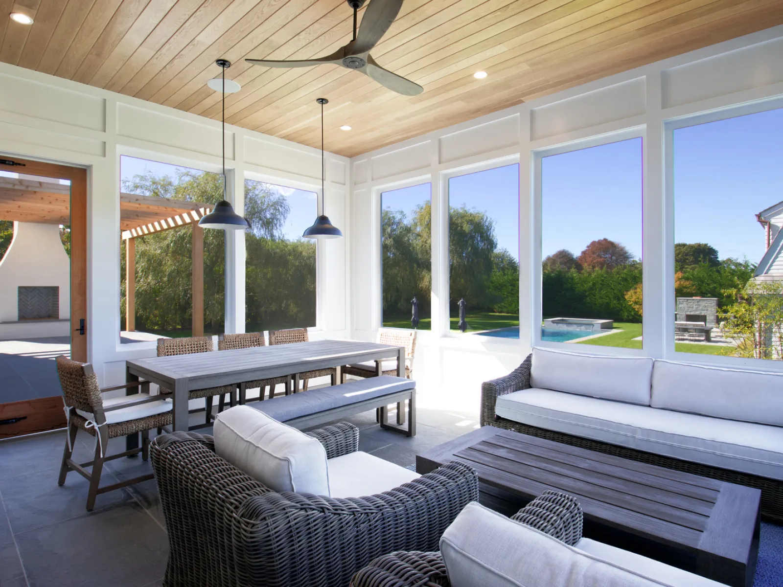Bright and airy sunroom with modern furniture, large windows, and views of the outdoor pool.