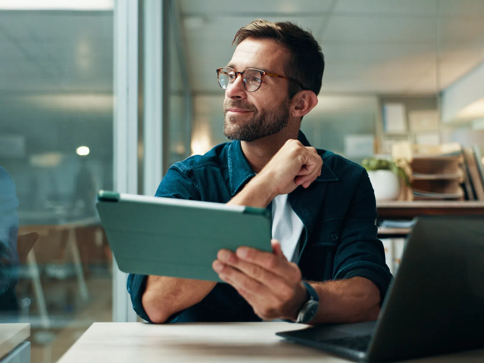 a woman sitting at a table with a laptop and a man standing behind her
