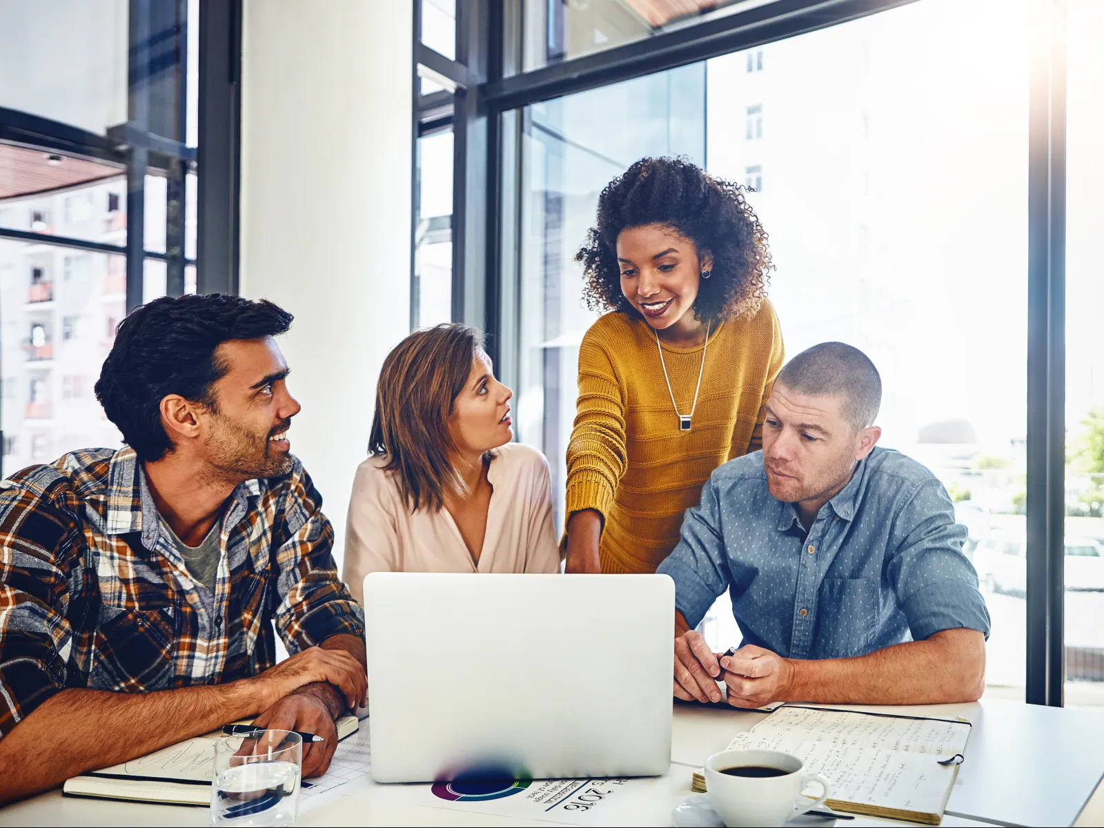 a group of people sitting around a table looking at a laptop