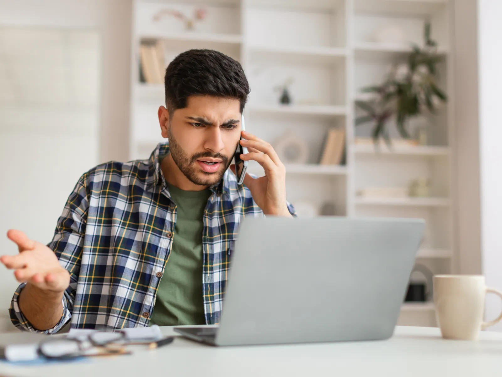 a person talking on the phone while using a laptop