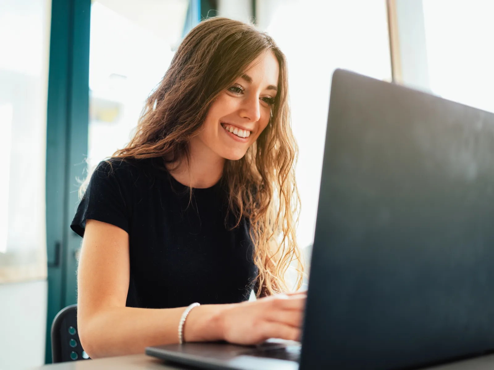 a woman smiling and working on a computer
