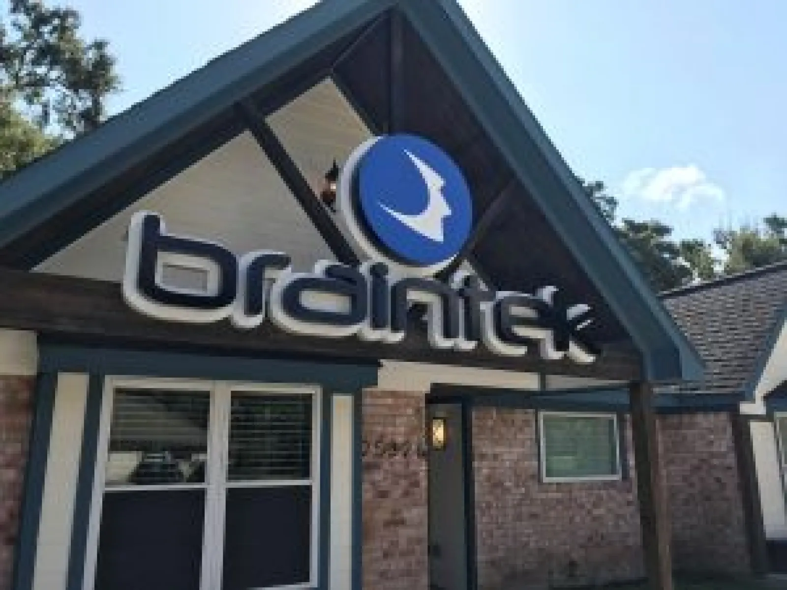 BrainTek company sign mounted on a building with brick walls and blue trim under a clear sky.